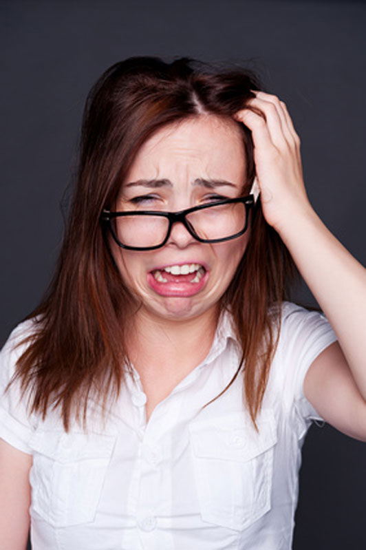 woman in glasses crying with hand on head