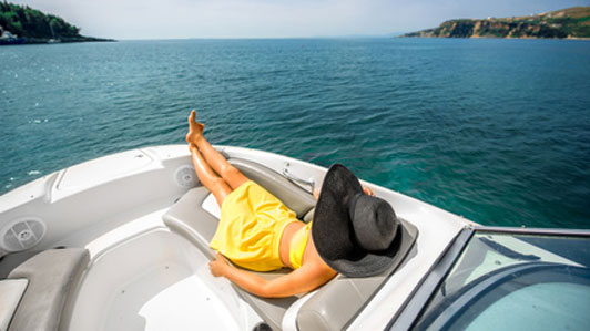 woman in large black hat relaxing on yacht