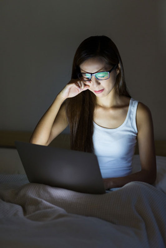 young women in bed on laptop