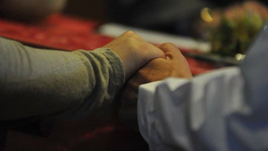 Couple holding hands while sitting at a table.