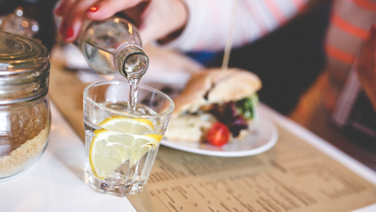 Girl puring water into a glass with lemon.