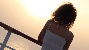 woman leaning on rail looking over open water