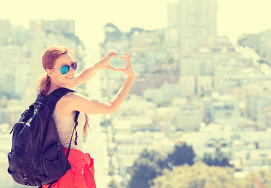 girl with heart sign on view of city