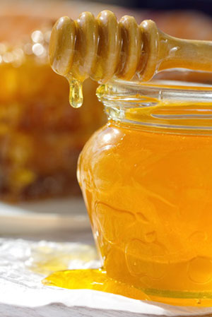 honey dripping from jar on table