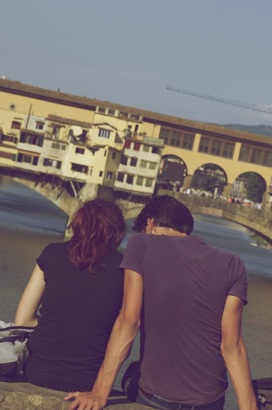guy and girl sitting together in front of bridge