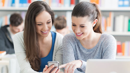 two woman looking at smartphone screen one pointing