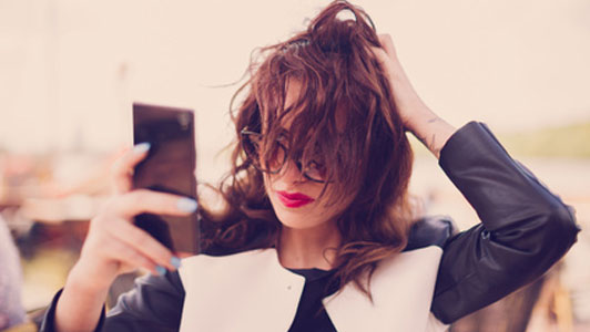 women fixing hair while taking selfie