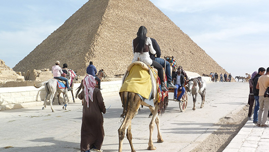 A pyramid and tourists riding camilles