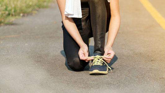 woman in middle of road tying shoes