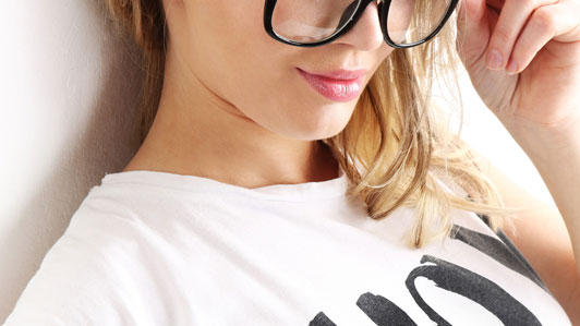 young woman wearing black eye glasses and white shirt with something written on it