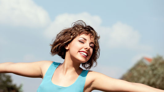 girl in light blue tank tops smiling with arms wide open