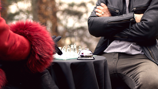 Woman with red fur playing glass chess with a guy