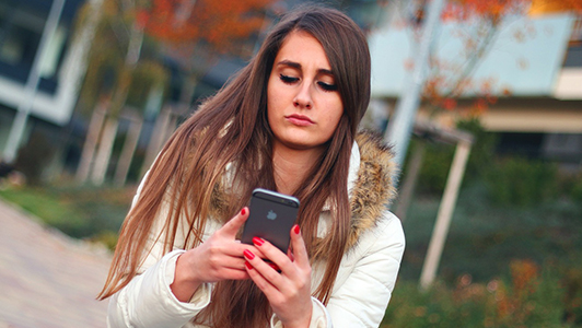 Girl with long hair texting on an iPhone