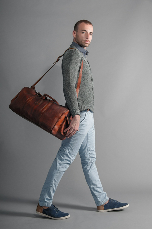 Guy in a sweater carrying a brown bag.