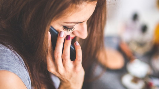 Girl with painted nails talking on a phone.