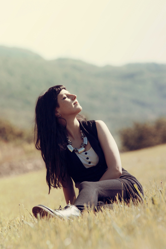 Girl sitting in the field with her eyes closed.