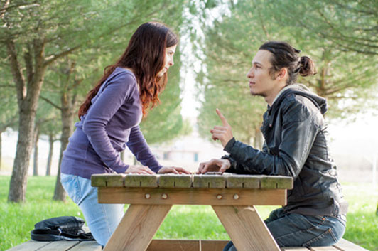 guy and girl in middle of a fight sitting on a park bench; quarrel of love