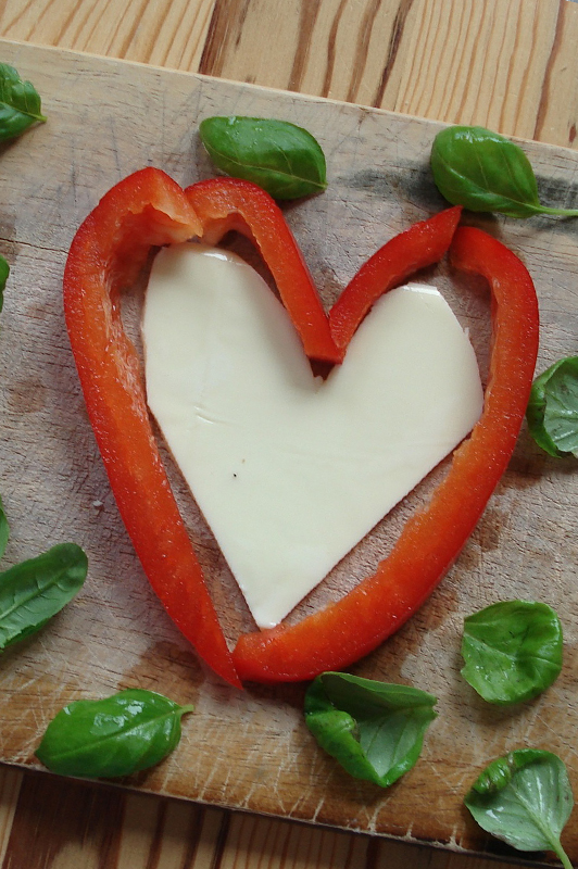 Heart made of paprika and cheese, with herbs sprinkled around.