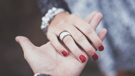 Guy holding a hand of a girl with red nails