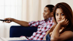 Man ignoring woman while watching TV
