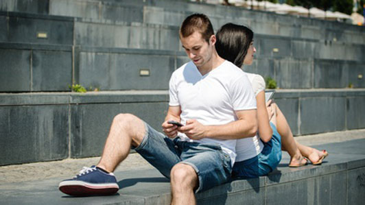 couple sitting back to back on phones