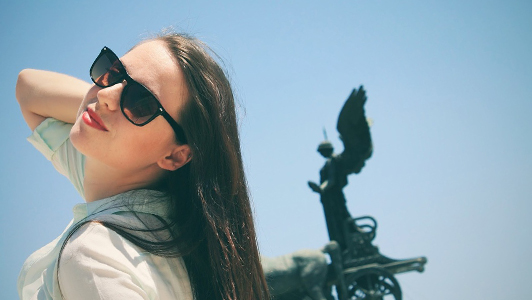 Girl with long hair and sunglasses smiling.