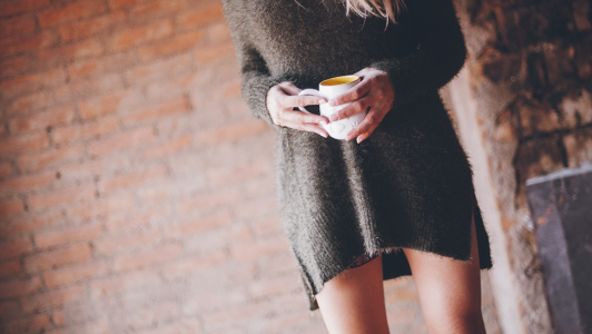 Girl in a long sweater holding a mug.