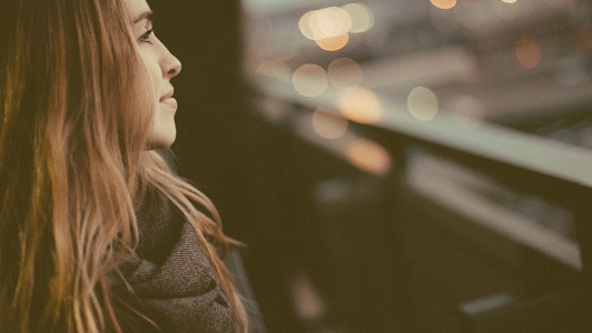 Girl with long hair and scarf looking away and smiling.