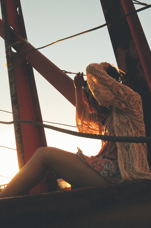 Girl in a dress sitting and touching her hair.