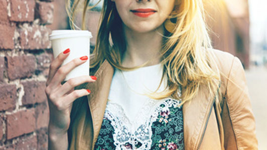 girl holding coffee cup outside standing next to brick building