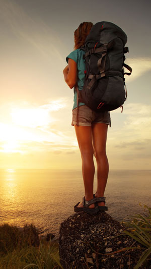 Girl with a backpack watching sunset.