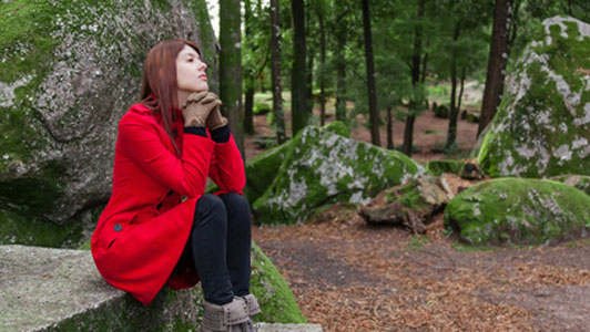 woman in red coat waiting on stone table alone