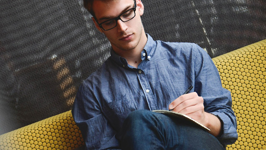 Guy in a denim shirt writing something down.