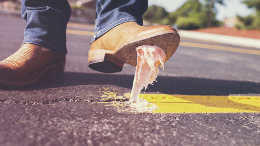 A gum on pavement stuch to a baige boot.