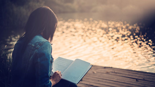 young woman reading lakeside