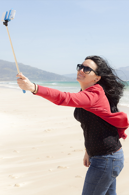 Woman taking a selfie using a selfie stick.