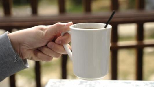 A hand holding a white mug