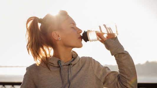 woman in sweatshirt drinking water