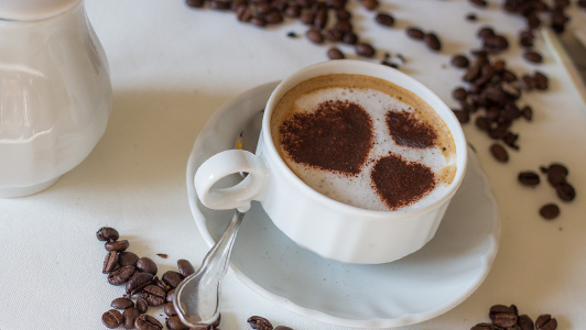 A cup of coffee with hearts made of ground coffee on top of the foam.