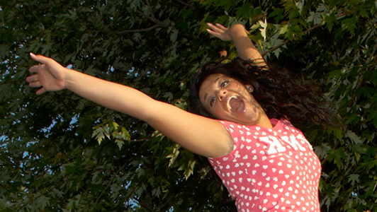 Girl in a pink shirt jumping and laughing.s