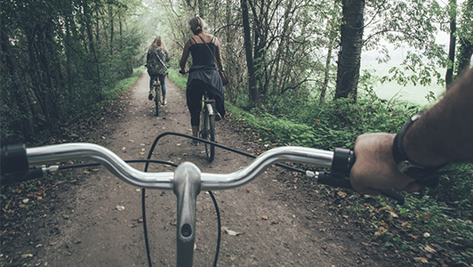 Two girls riding a bike in the forest