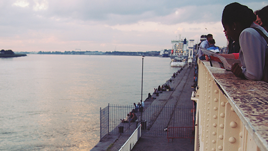 People sitting lined up on the side of a river.