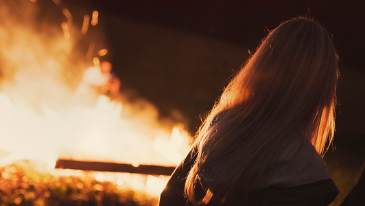 Girl with long hair looking at fire.