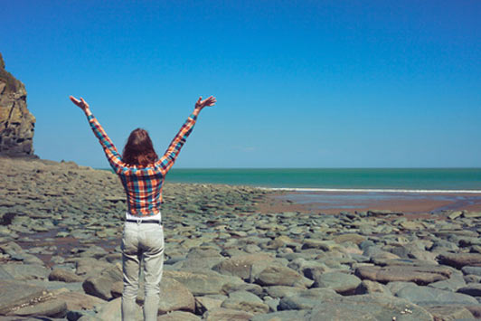 woman with arms wide open at beach