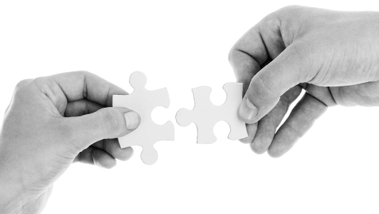 Two hands holding a puzzle piece each.