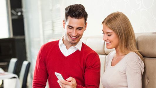 woman showing interest in what show is shown on phone by man