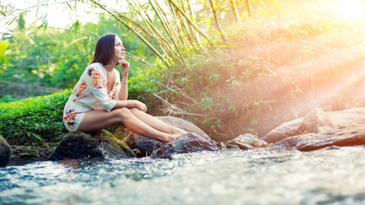 woman in white floral dress sitting alone thinking riverside