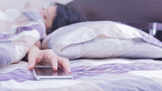 woman asleep reaching for smartphone