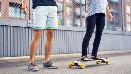 man and woman fooling around with scateboard