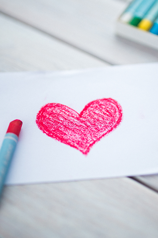 A drawing of a heart and a crayon laid next to it